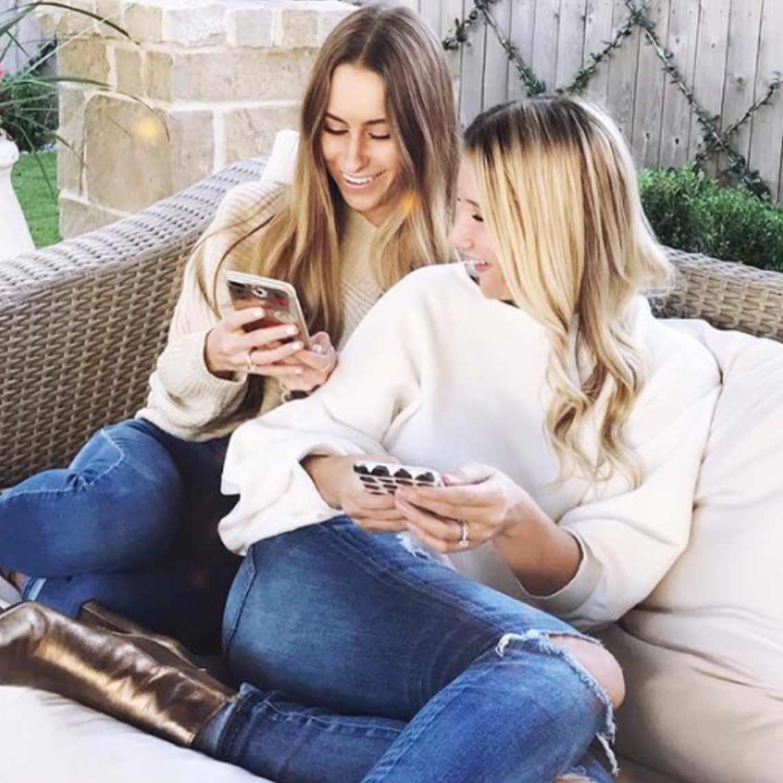 Two women sitting outside talking and using their cell phones. Two women sitting outside talking and using their cell phones.