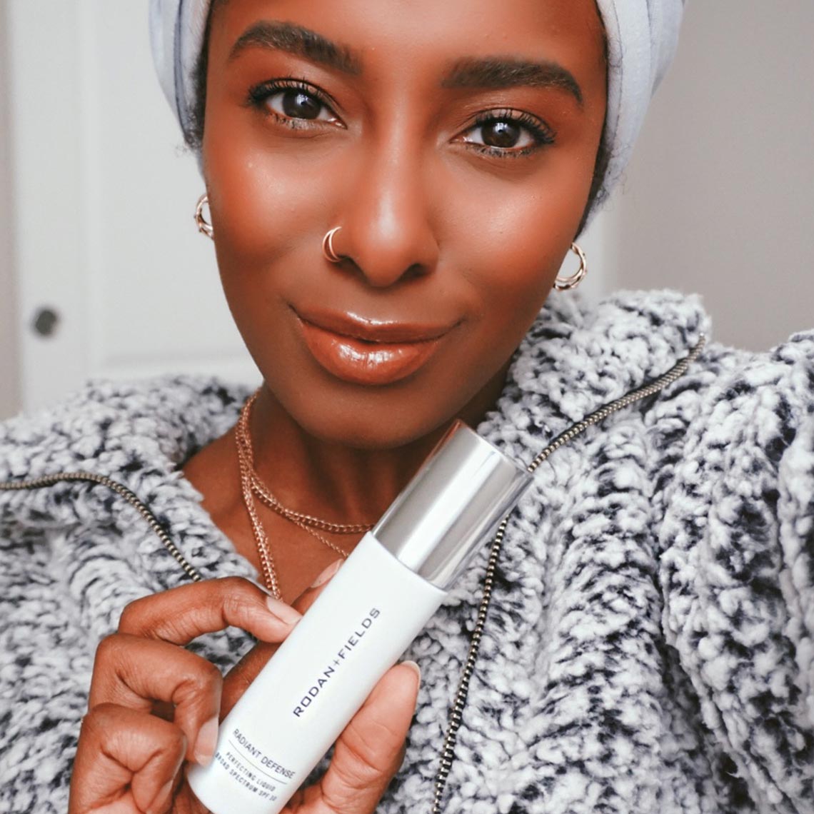 Woman holding Rodan and Fields Radiant Defense Perfecting Liquid SPF 30. Woman holding Rodan and Fields Radiant Defense Perfecting Liquid SPF 30.